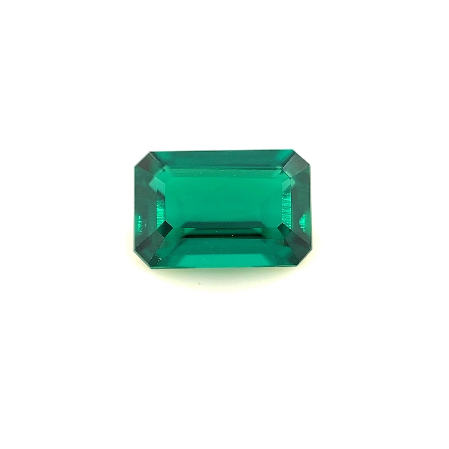 A 9.0x6.0 exceptional Zambian color lab created emerald, emerald-cut with beveled edges, is displayed on a plain white background.