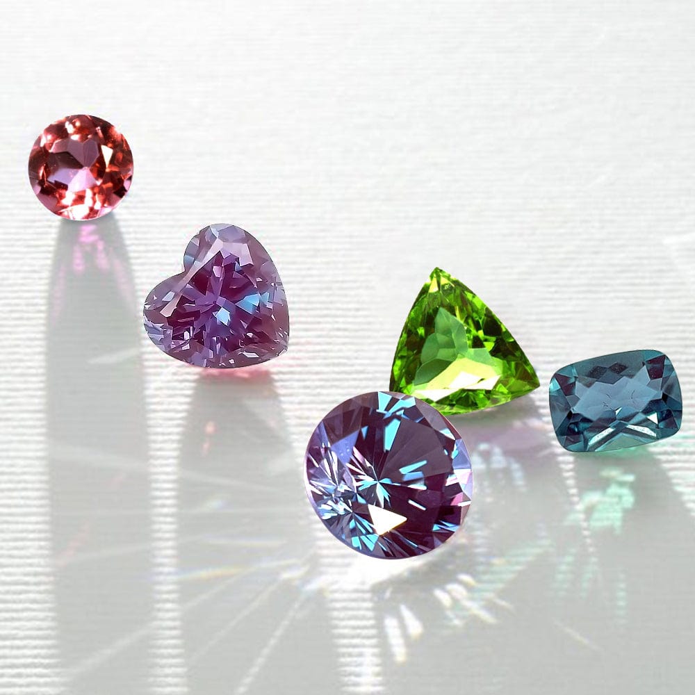 Five colorful alexandrite gemstones on a reflective surface