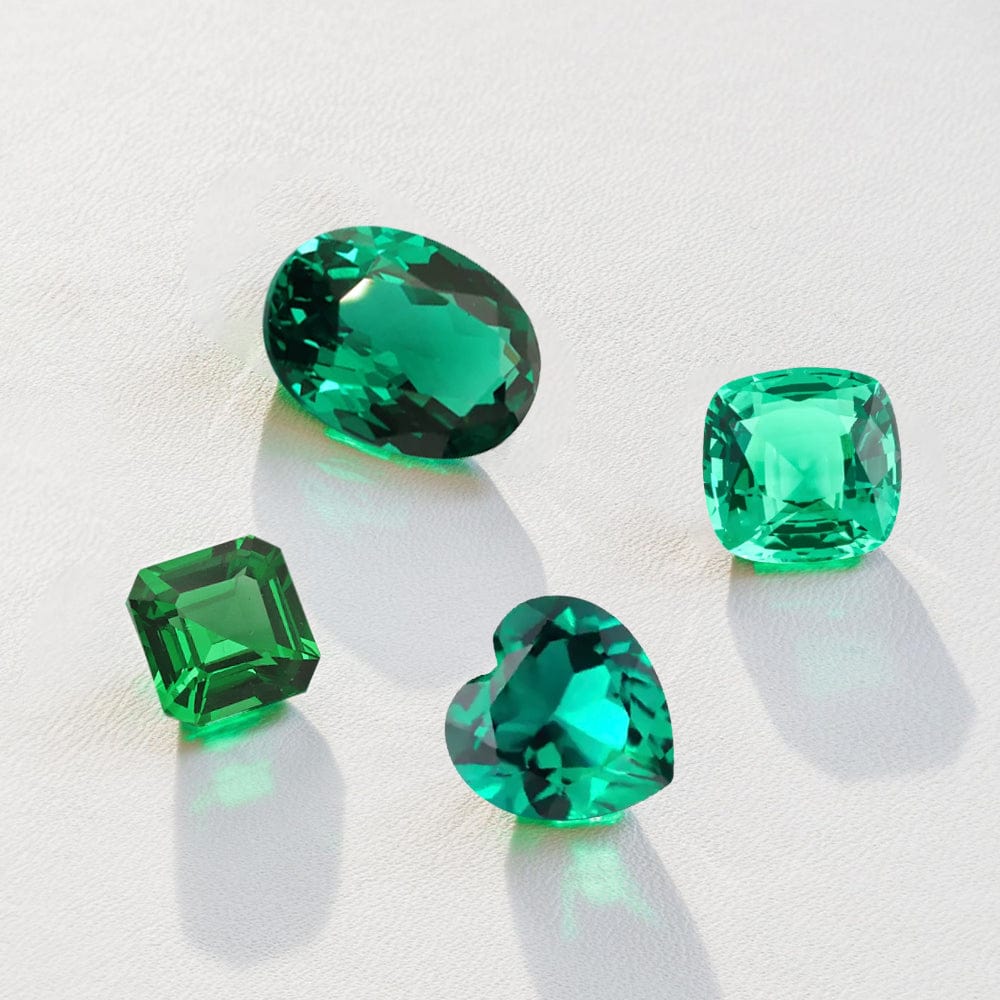 Four green emerald gemstones on a light background