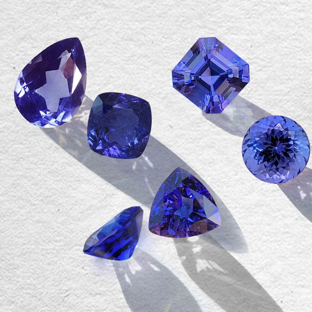 Collection of blue tanzanite gemstones on a textured white background