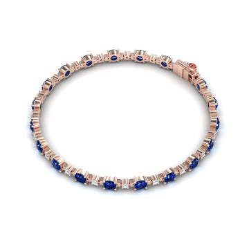 The Blue Sapphire & Diamond Tennis Bracelet - Natalia features alternating round blue sapphires and small white diamonds set symmetrically in a rose gold band.