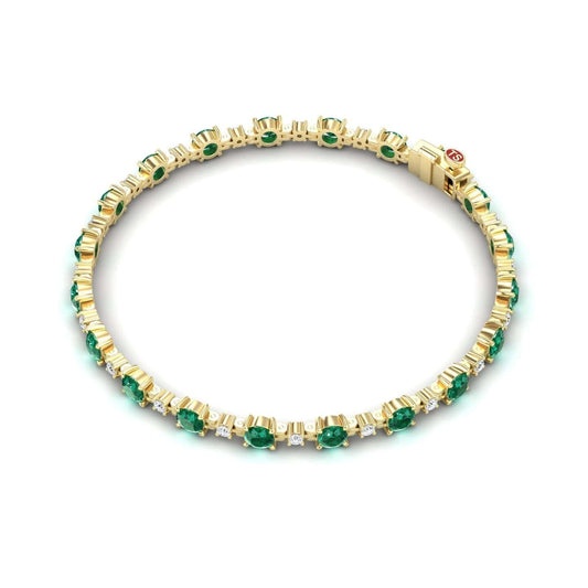 The Emerald & Diamond Tennis Bracelet - Natalia features alternating green emeralds and small clear diamonds on a gold band with a secure clasp, shown on a white background.