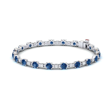 The London Blue Topaz & Diamond Tennis Bracelet - Natalia features round blue gemstones in prong settings, shown on a white background.