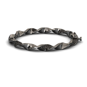 The Black Diamond Twisted Bangle Bracelet - Dakota features a sleek metallic design with embedded dark stones, a twisted motif, and a secure clasp for an elegant, modern look.
