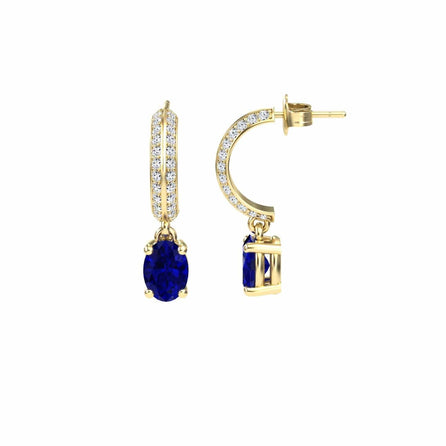 The Serena Blue Sapphire & Diamond Huggie Drop Earrings are shown from front and side views, featuring gold hoops adorned with small white diamonds and a dangling oval-shaped deep blue sapphire, displayed on a white background.