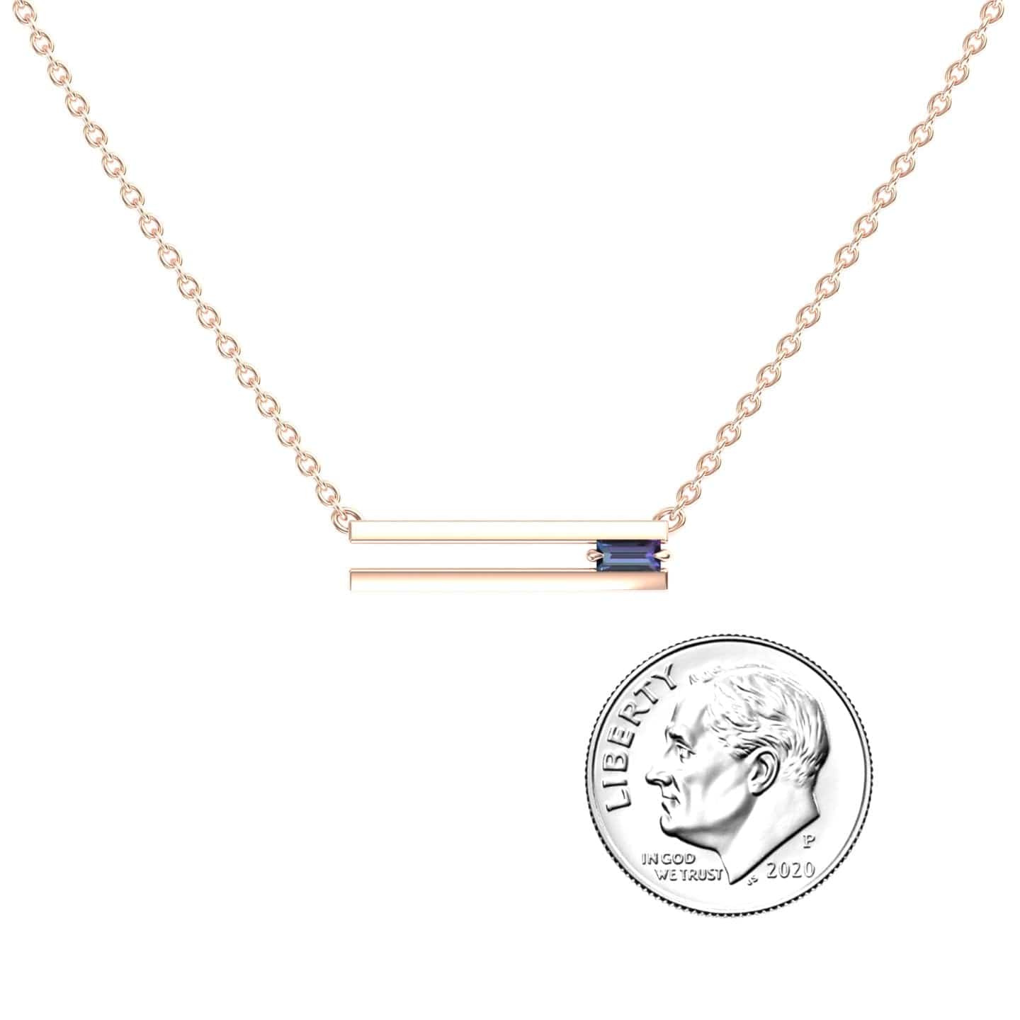 The Lab Grown Alexandrite Bar Necklace - Cecilia features a gold chain and a horizontal bar pendant with a small blue rectangular accent, shown beside a 2020 U.S. dime on a white background for size reference.