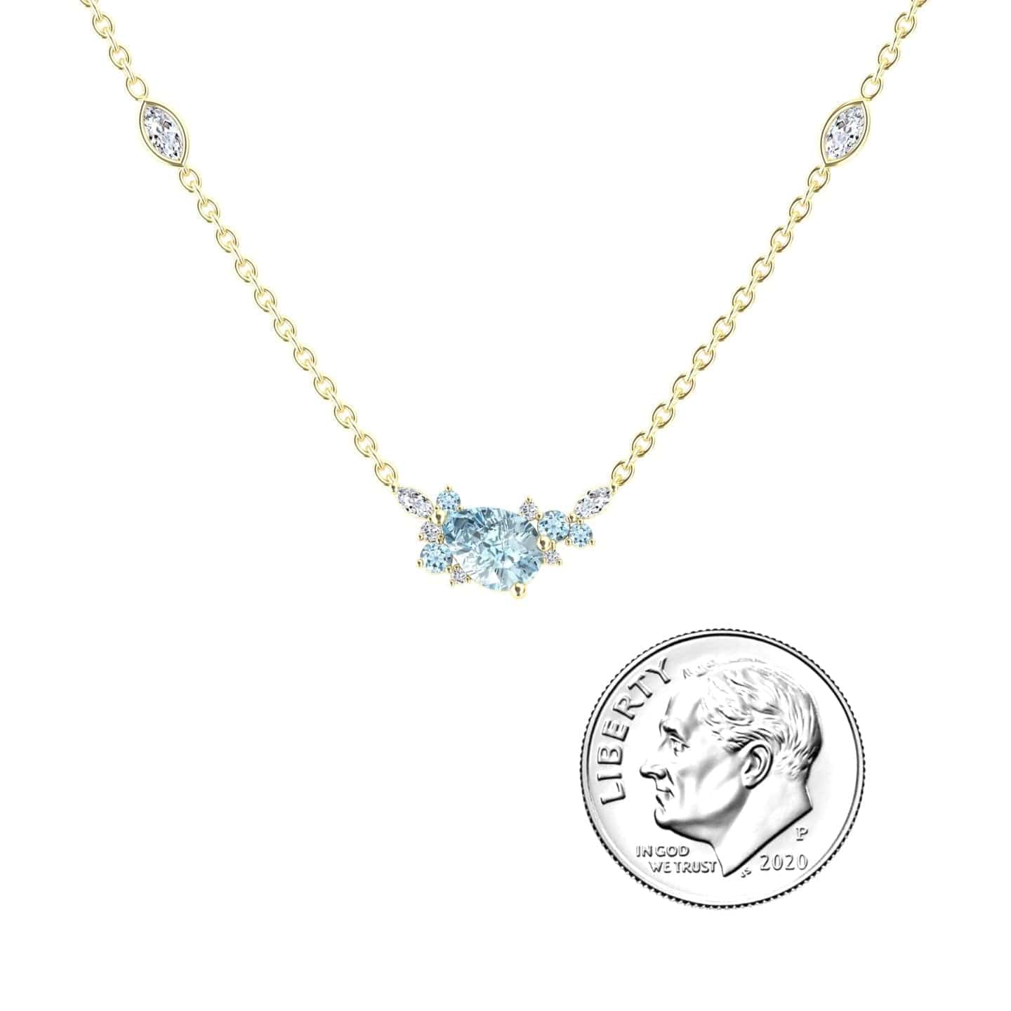 The Aquamarine & Diamond Bouquet Necklace - Daria features a delicate gold chain with a central blue aquamarine and small diamonds, shown next to a 2020 U.S. dime for size reference.