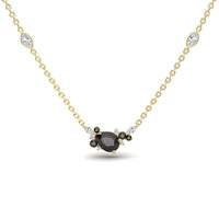 The Black & White Diamond Bouquet Necklace – Daria features a gold chain with a central oval black gemstone, surrounded by black and white stones, plus two marquise-shaped white stones set along the chain.