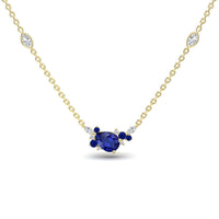 The Blue Sapphire & Diamond Bouquet Necklace - Daria features a gold chain with a central pear-shaped blue gemstone, accented by small blue and white stones and two marquise-cut white stones along the chain.