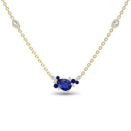 The Blue Sapphire & Diamond Bouquet Necklace - Daria features a gold chain with a central pear-shaped blue gemstone, accented by small blue and white stones and two marquise-cut white stones along the chain.