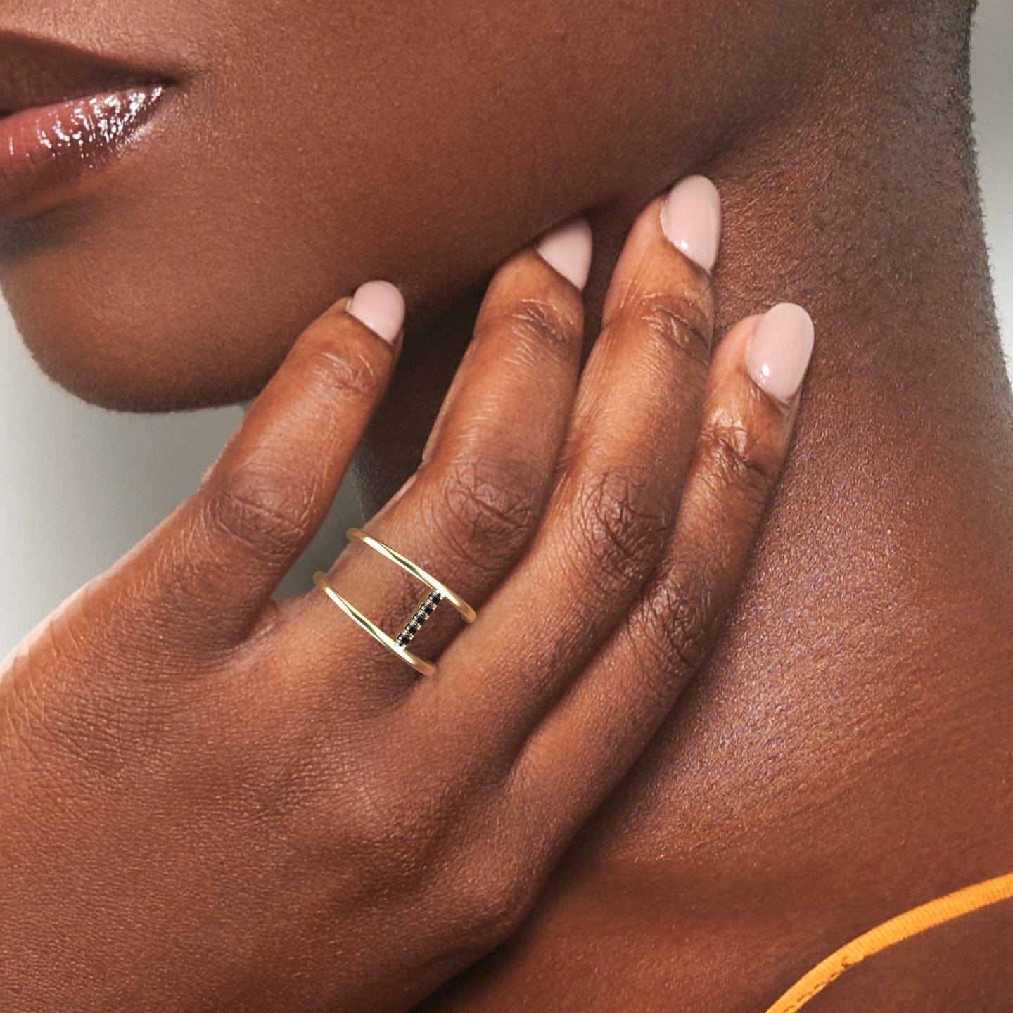 A person with medium-dark skin gently touches their neck, highlighting the Black Diamond Vertical Bar Split Band Ring - Opal on their finger. Their nails are manicured in pale pink polish.
