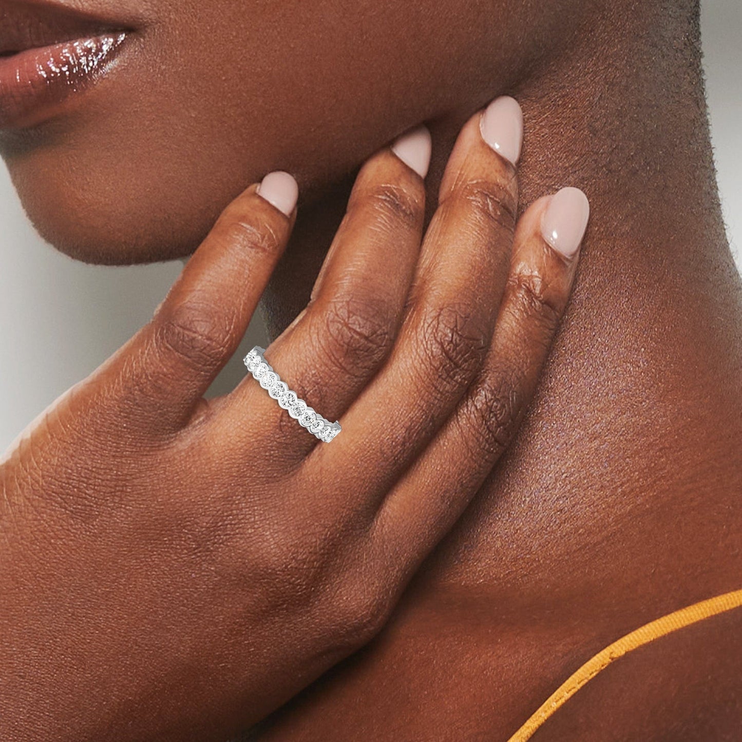 Close-up of a hand wearing a diamond ring with a neutral background