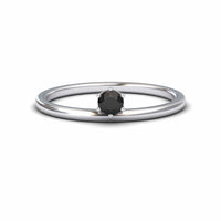 The Black Diamond Solitaire Petite Ring - Faria features a single round black diamond held by six prongs in a simple silver band, shown against a plain white background.