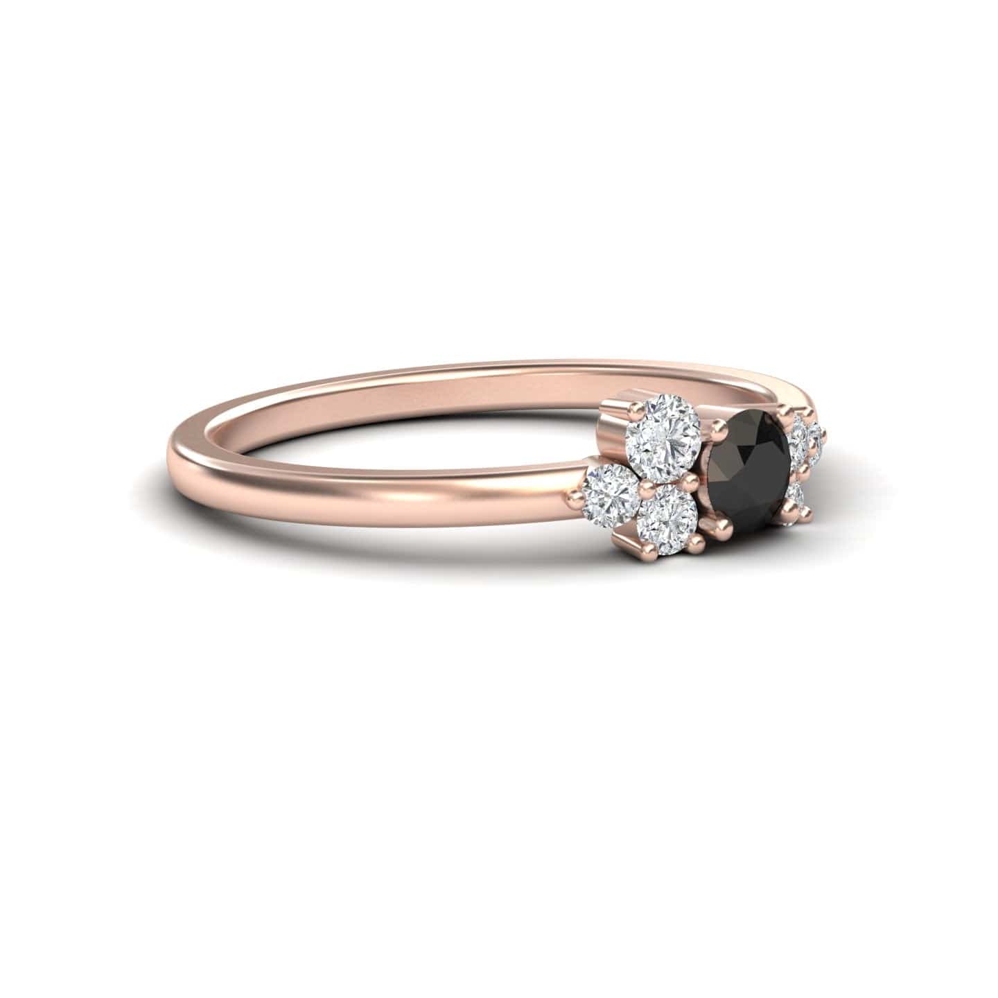 The Liana Black & White Diamond Cluster Ring features a round black center stone with clusters of sparkling white diamonds on each side, crafted in delicate rose gold for an elegant, minimalistic look.