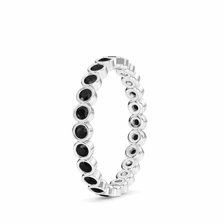 The Zara Black Diamond Bezel Set Eternity Band Ring features round black gemstones encircling the band, showcased upright against a white background.