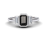 The Black & White Diamond Three-Stone Art Deco Ring - Ivy features a rectangular black gemstone center, flanked by two smaller baguette-cut clear stones on each side, shown against a white background.
