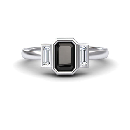 The Black & White Diamond Three-Stone Art Deco Ring - Ivy features a rectangular black gemstone center, flanked by two smaller baguette-cut clear stones on each side, shown against a white background.