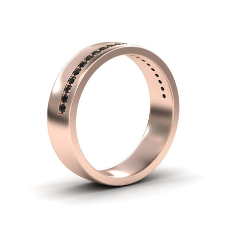 The Mens Black Diamond Channel-Set Wedding Band - Yan features a sleek rose gold band with a polished finish and a diagonal channel of small black diamonds, showcased against a white background.