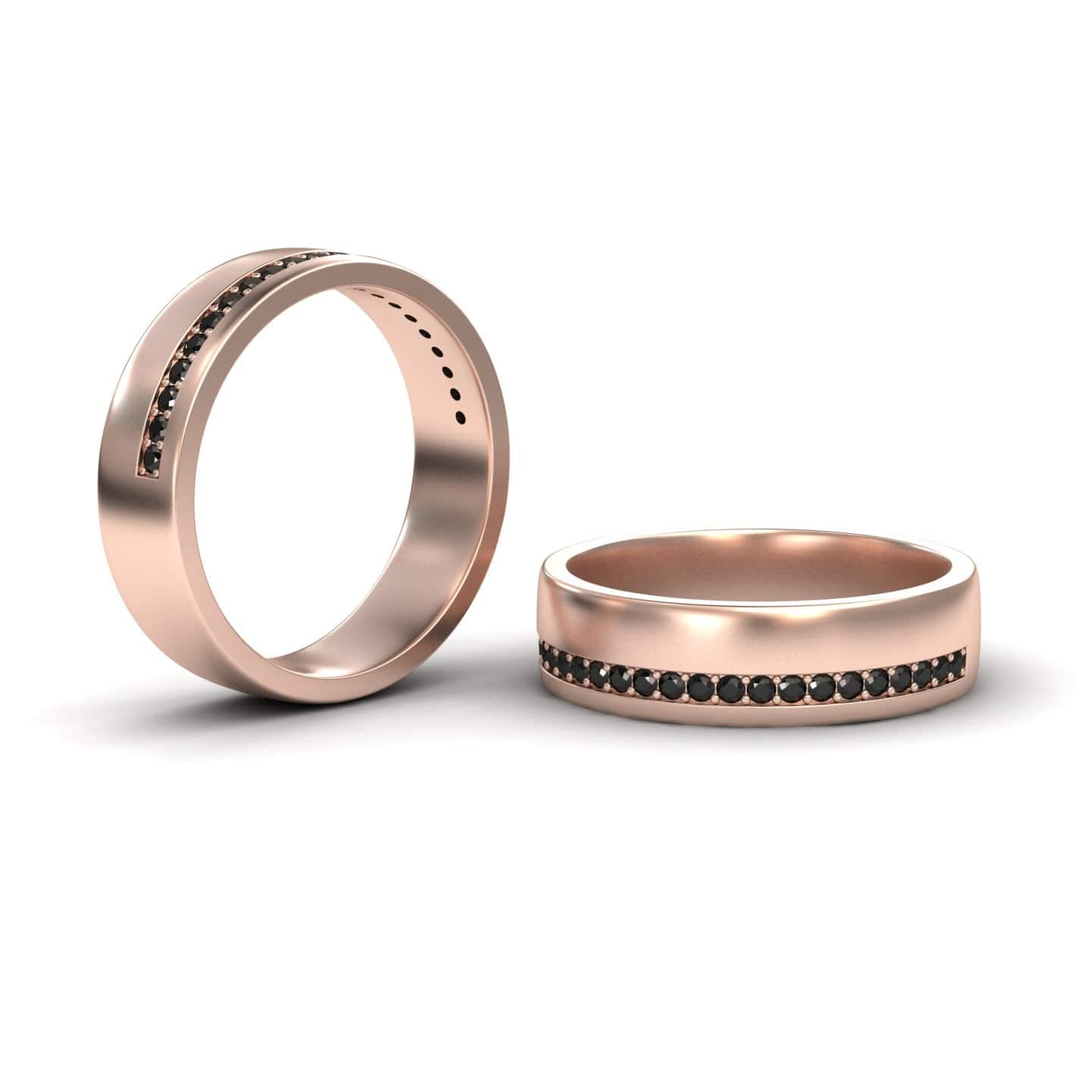 Two Men’s Black Diamond Channel-Set Wedding Bands - Yan, in rose gold with a row of small black diamonds around the center, displayed on a white background; one ring stands upright while the other lies flat.