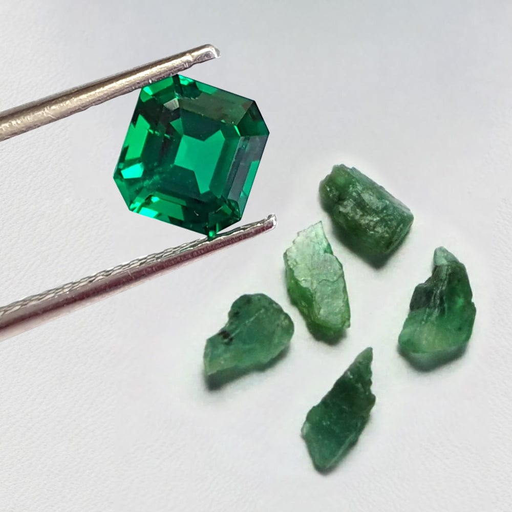 Green emerald gemstone and its rough counterpart on a white background