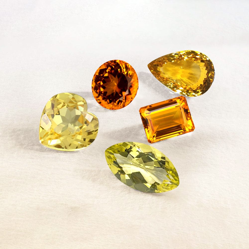 Five yellow and orange citrine gemstones on a light beige background