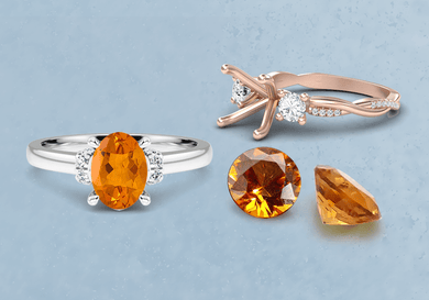 Two rings with orange citrine gemstones on a light blue background