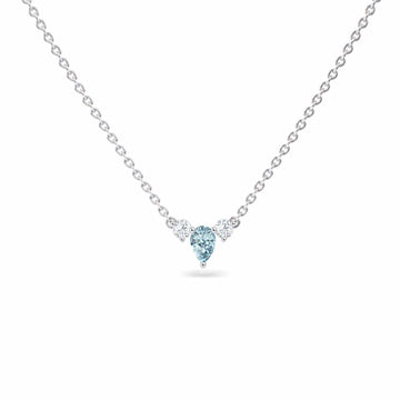 The Aquamarine & Diamond Three-Stone Necklace - Jina features a delicate silver chain with a central blue heart-shaped gemstone and two round clear stones, shown on a white background.
