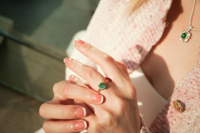 A woman wearing an emerald ring paired with an emerald pendant