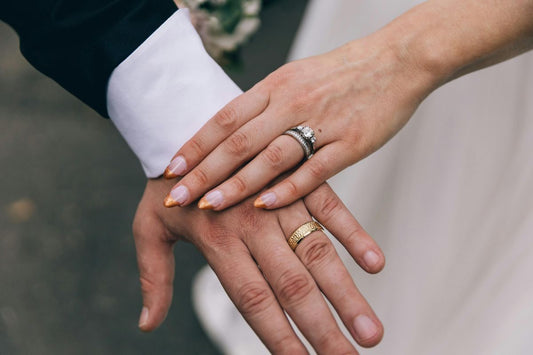 Close-up of hands wearing an engagement ring and wedding band.