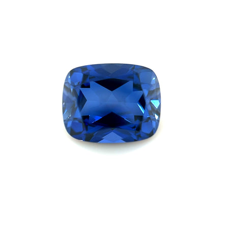 The 10.0x8.0 Exceptional Cushion Lab Created Blue Sapphire, renowned for its deep blue color and multiple facets, is displayed against a plain white background.