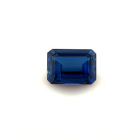 The 7.0x5.0 Exceptional Emerald Lab Created Blue Sapphire features a deep blue color and sharp, faceted edges, beautifully showcased against a plain white background.