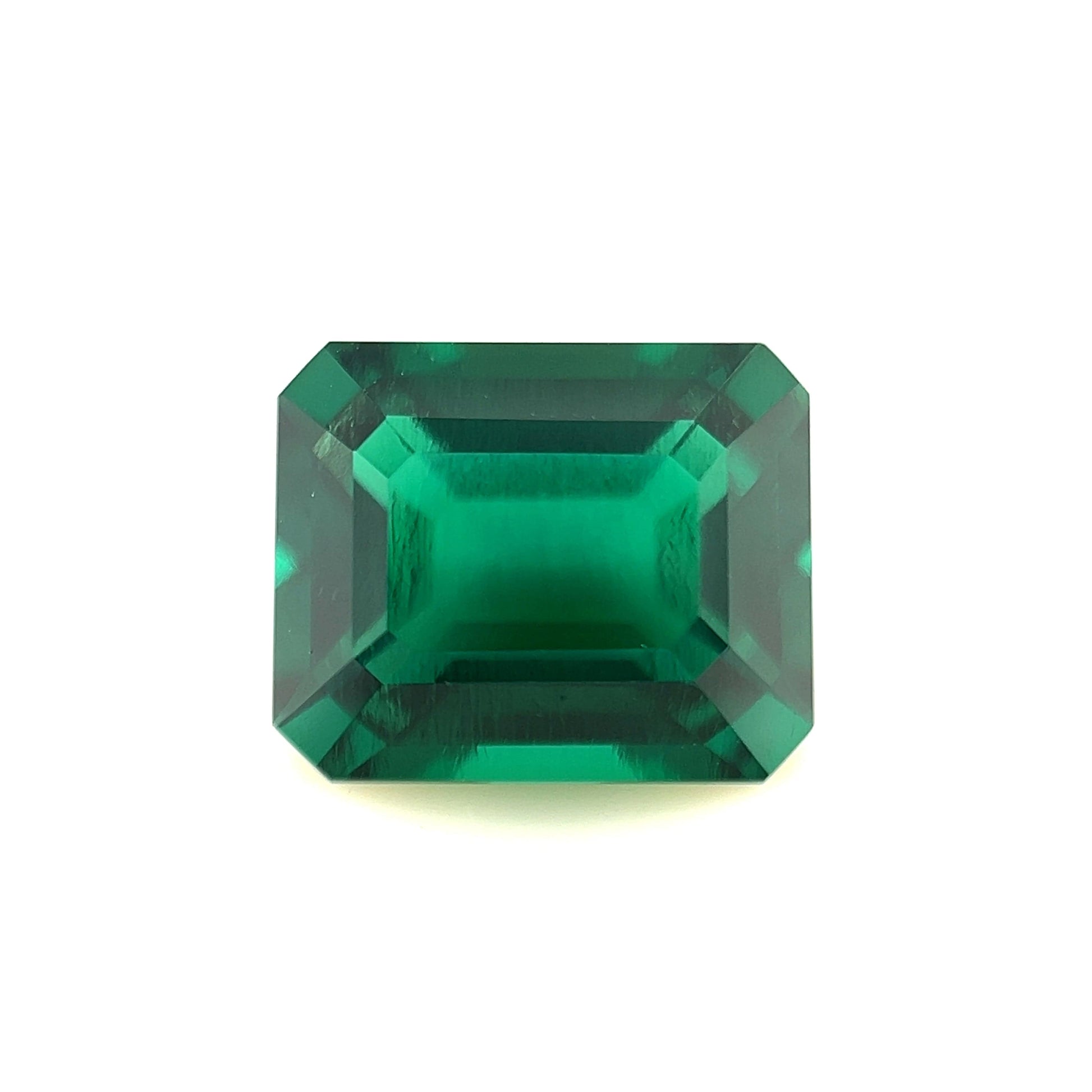 An 11x9 exceptional Zambian color lab-created emerald with a rectangular, emerald cut and beveled edges, shown against a white background.
