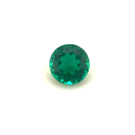 The 5.5mm Exceptional Round Zambian Color Lab Created Emerald is shown against a plain white background, highlighting its vibrant green hue and sparkling facets.