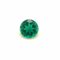 The 6mm Exceptional Round Zambian Color Lab Created Emerald features a vivid green hue and a unique star-shaped pattern at its center, shown against a plain white background.