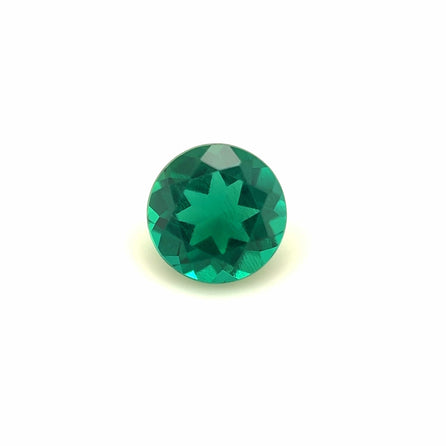The 6mm Exceptional Round Zambian Color Lab Created Emerald features a vivid green hue and a unique star-shaped pattern at its center, shown against a plain white background.