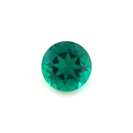 A 6.5mm Exceptional Round Zambian Color Lab Created Emerald, faceted with a star-shaped center pattern, displayed on a plain white background.