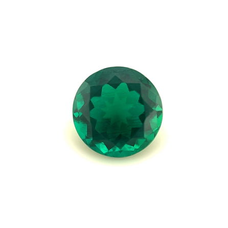 An 8mm Exceptional Round Zambian Color Lab Created Emerald, showcasing a symmetrical star-like pattern at its center, is displayed on a plain white background.