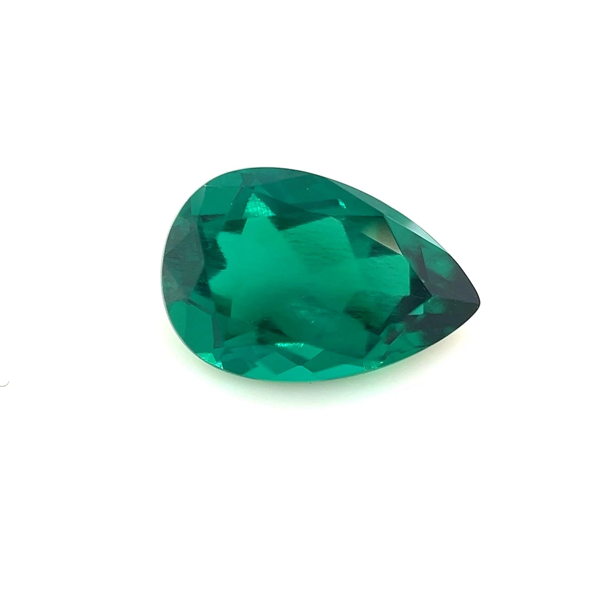 The 12.0x8.0 Exceptional Pear Zambian Color Lab Created Emerald is shown against a plain white background, highlighting its vivid green color and brilliant, reflective surface.
