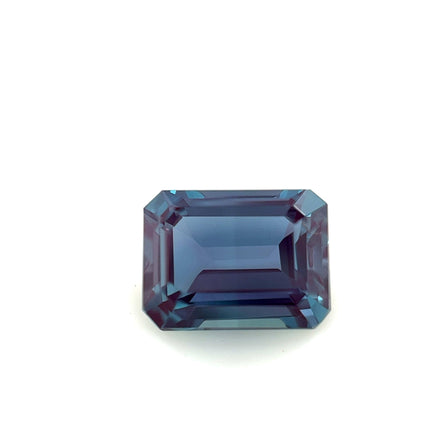The 8.0x6.0 Exceptional Emerald Lab Created Alexandrite features rich blue and purple hues in a rectangular emerald cut, displayed against a simple white background to highlight its outstanding quality.