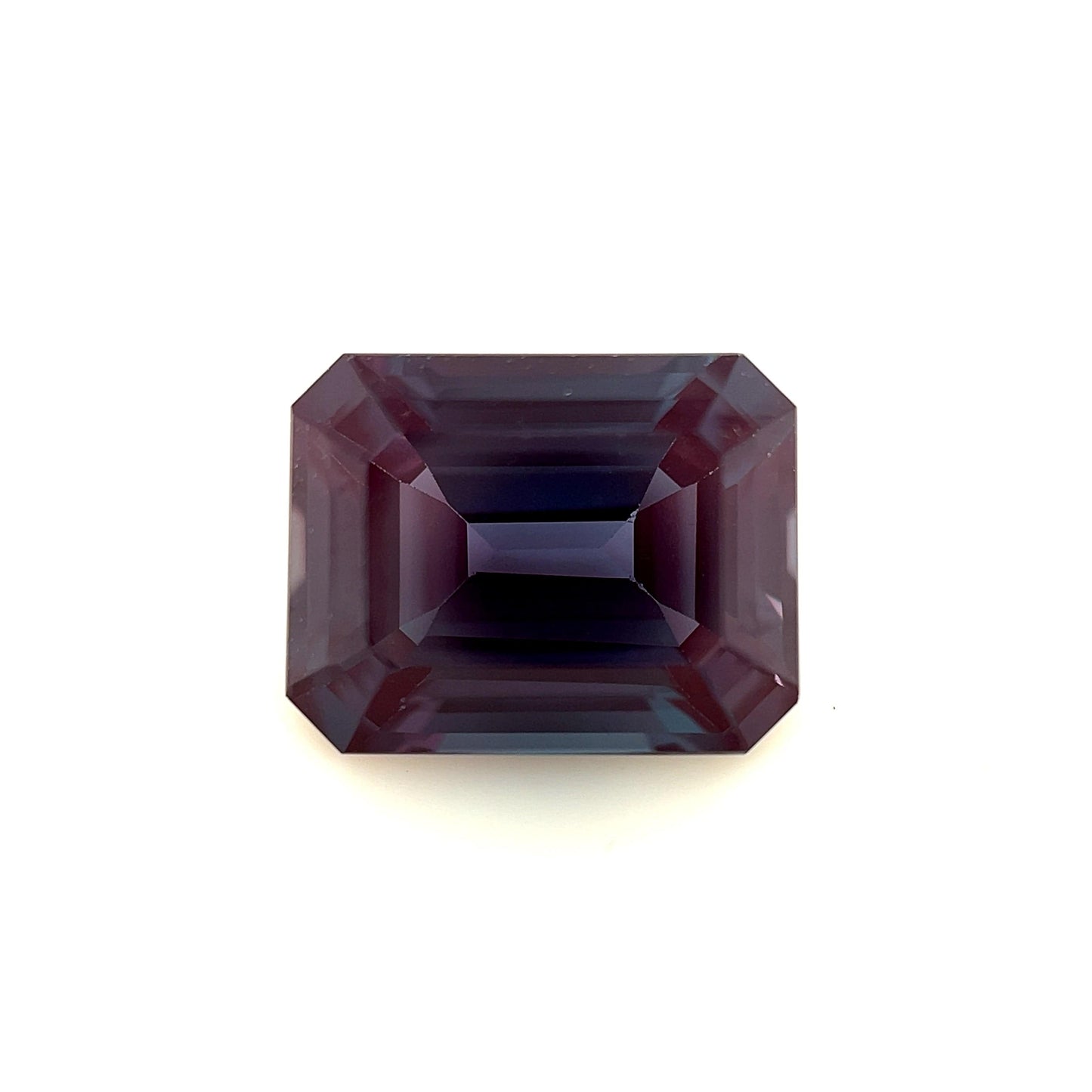 A 10.0x8.0 exceptional emerald-cut lab created Alexandrite with deep purple hues and sharp facets is displayed against a plain white background.