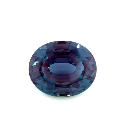 A 12.0x10.0 Exceptional Oval Step Lab Created Alexandrite with deep blue and purple hues is displayed on a white background.