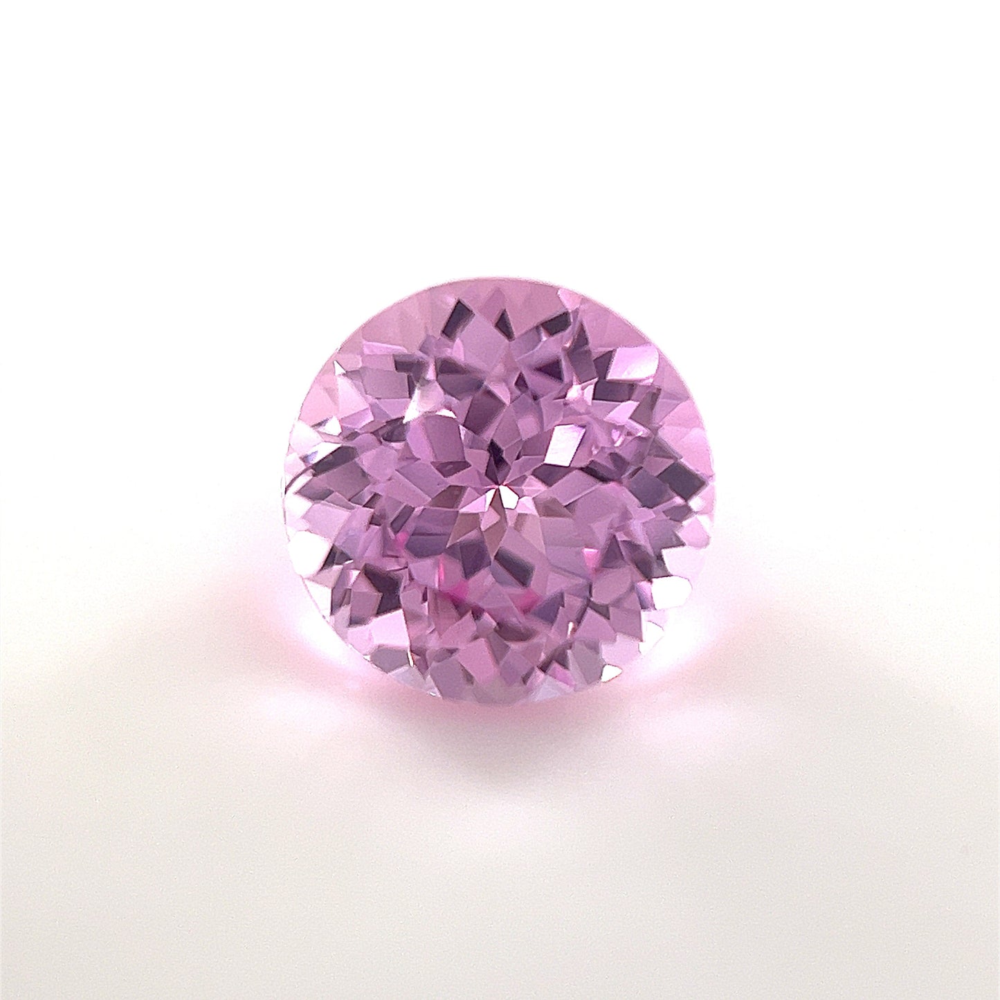 The 8mm Exceptional Round Lab Created Medium Pink Sapphire features a brilliant cut and medium pink hue, elegantly displayed on a white background.