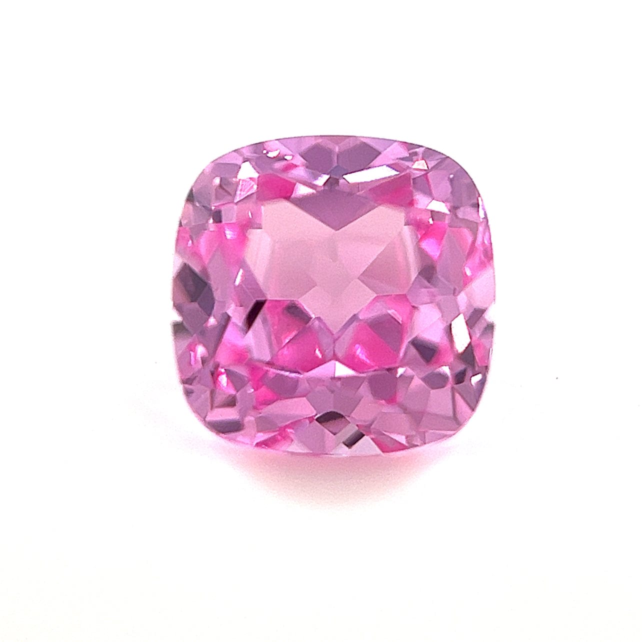 The 8mm Exceptional Cushion Lab Created Medium Pink Sapphire features faceted surfaces with pink and purple hues, shown against a plain white background.