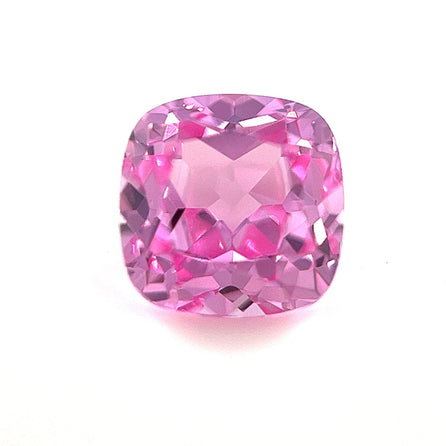 The 8mm Exceptional Cushion Lab Created Medium Pink Sapphire features faceted surfaces with pink and purple hues, shown against a plain white background.