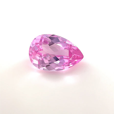 A 9x6 Exceptional Pear Lab Created Medium Pink Sapphire with a faceted surface is shown on a plain white background, highlighting its brilliant reflectivity and vibrant medium pink hue.