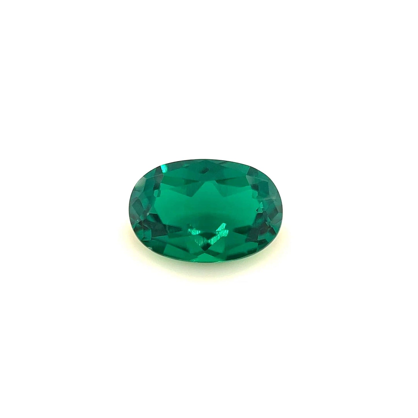 The 9.0x6.0 Exceptional Oval Zambian Color Lab Created Emerald features a faceted, vivid green stone that glows brightly against a plain white background.