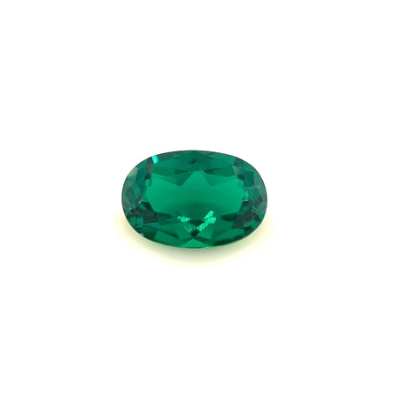 The 9.0x6.0 Exceptional Oval Zambian Color Lab Created Emerald features a faceted, vivid green stone that glows brightly against a plain white background.