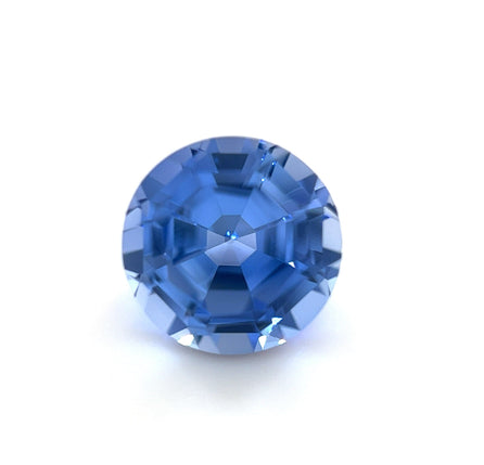 An 8mm Exceptional Round Step Lab Created Light Blue Sapphire, expertly faceted, is displayed against a white background, highlighting its sparkling reflections and intricate cuts.