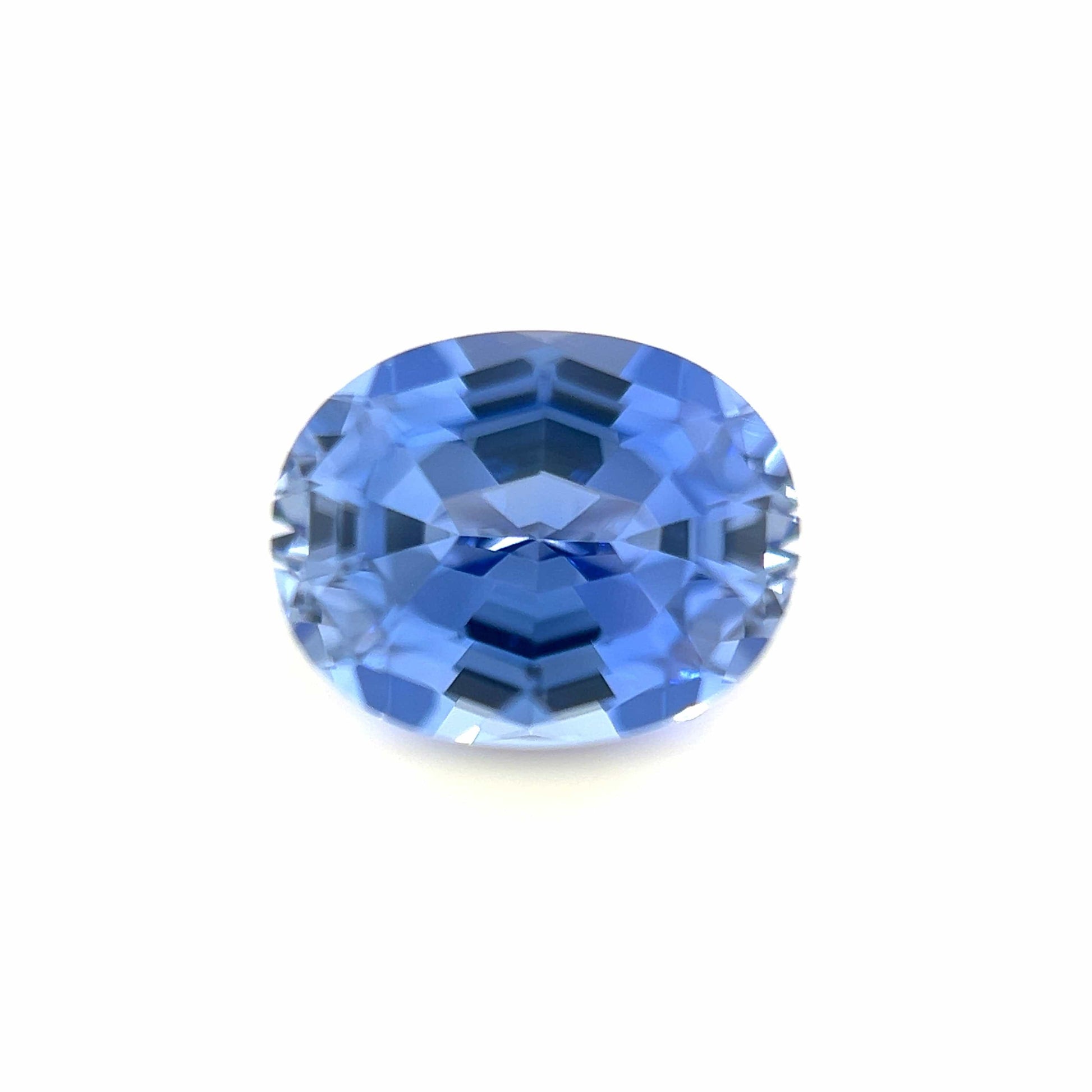The 9.0x7.0 Exceptional Oval Step Lab Created Light Blue Sapphire features an oval cut and step facets, displaying a vibrant light blue hue set against a plain white background.