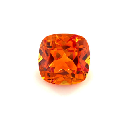An 8mm Exceptional Cushion Lab Created Orange Sapphire with brilliant facets reflecting light, displayed against a plain white background.